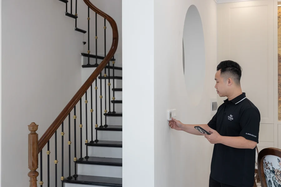 Personne réglant un thermostat mural dans l'entrée d'une maison
