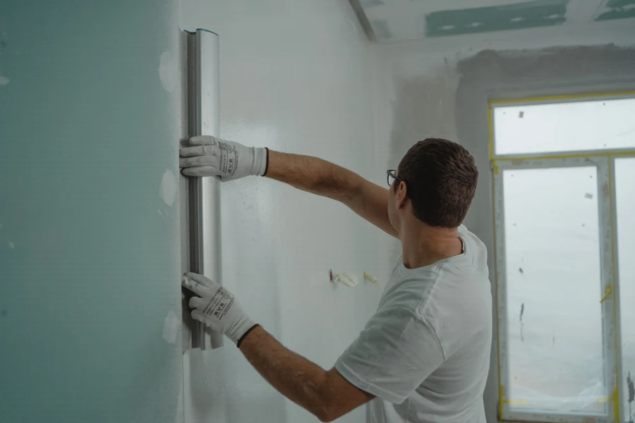 Plaquiste lissant un enduit sur des plaques de plâtre dans un logement en rénovation